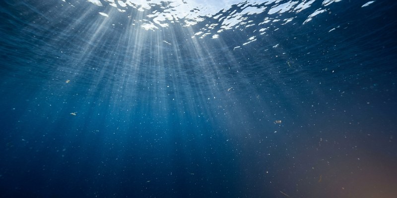 Fondo marino azul y vacío con rayos de sol atravesando el agua